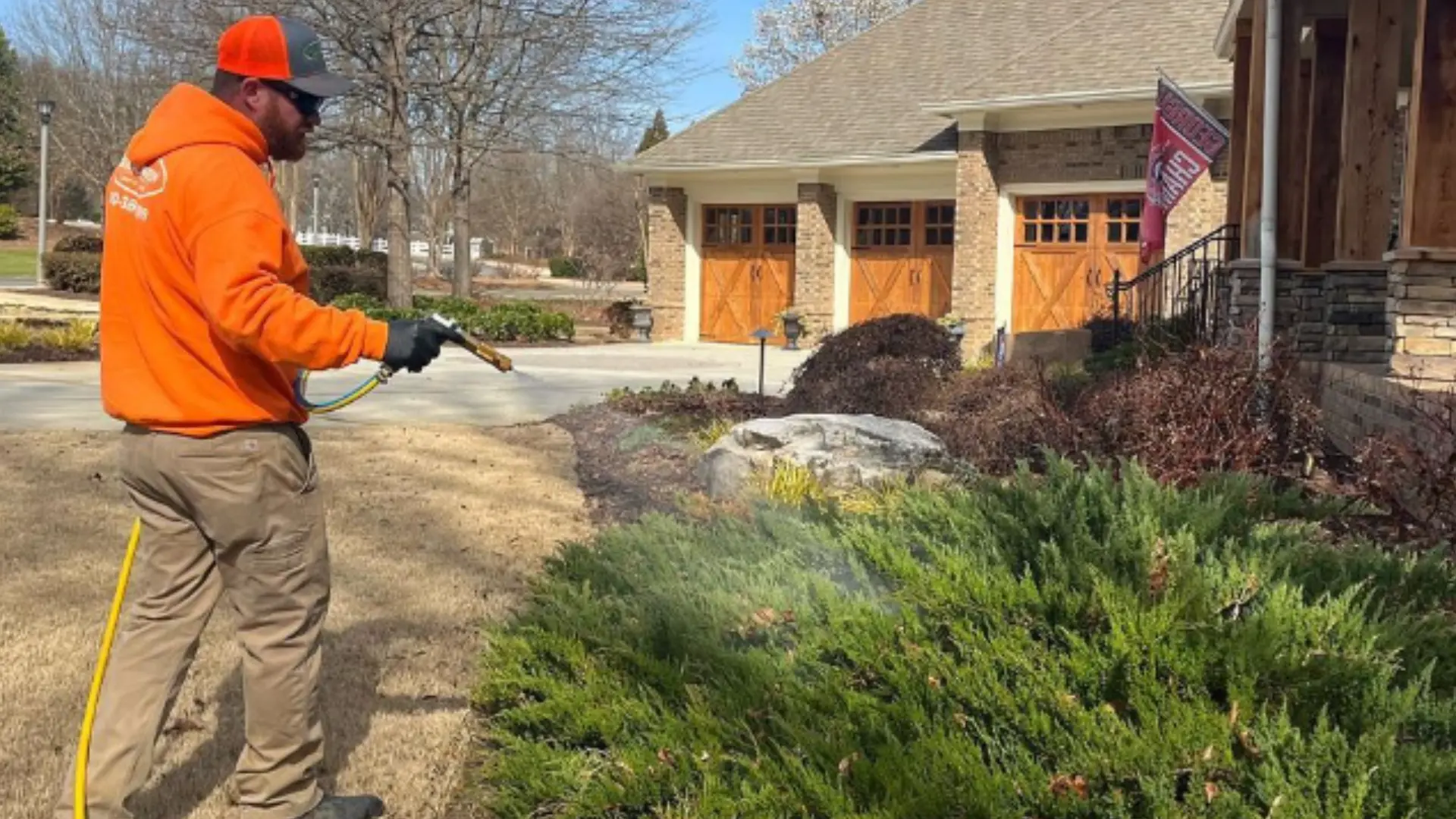 Solid Green Lawn & Landscape employee spraying shrubs.